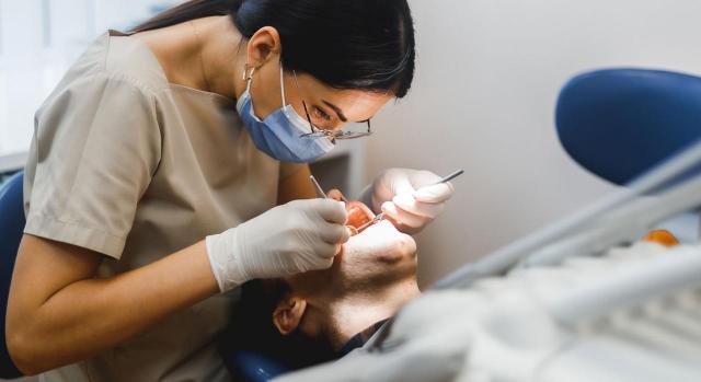 Permiso retribuido de hasta 35 horas al año reconocido por convenio para asistencia a consultas médicas. Imagen de una consulta de dentista en el que la doctora está haciendo un tratamiento a un hombre