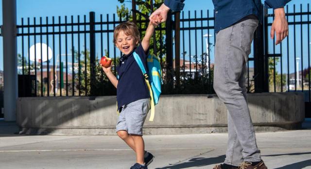 Solicitud de reducción de jornada por guarda legal por dos trabajadores de la misma empresa y del mismo departamento por el mismo sujeto causante. ¿Qué ocurre si ambos no se solapan? Imagen de un padre de la mano de su hijo saltando por la calle